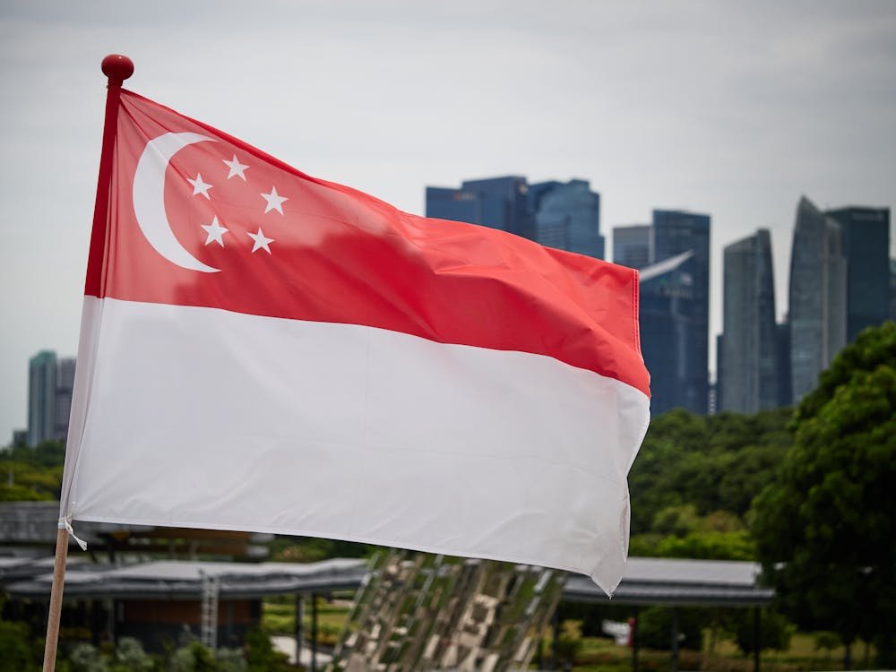 Singapore national flag waving with city skyline backdrop, symbolizing pride and modernity.