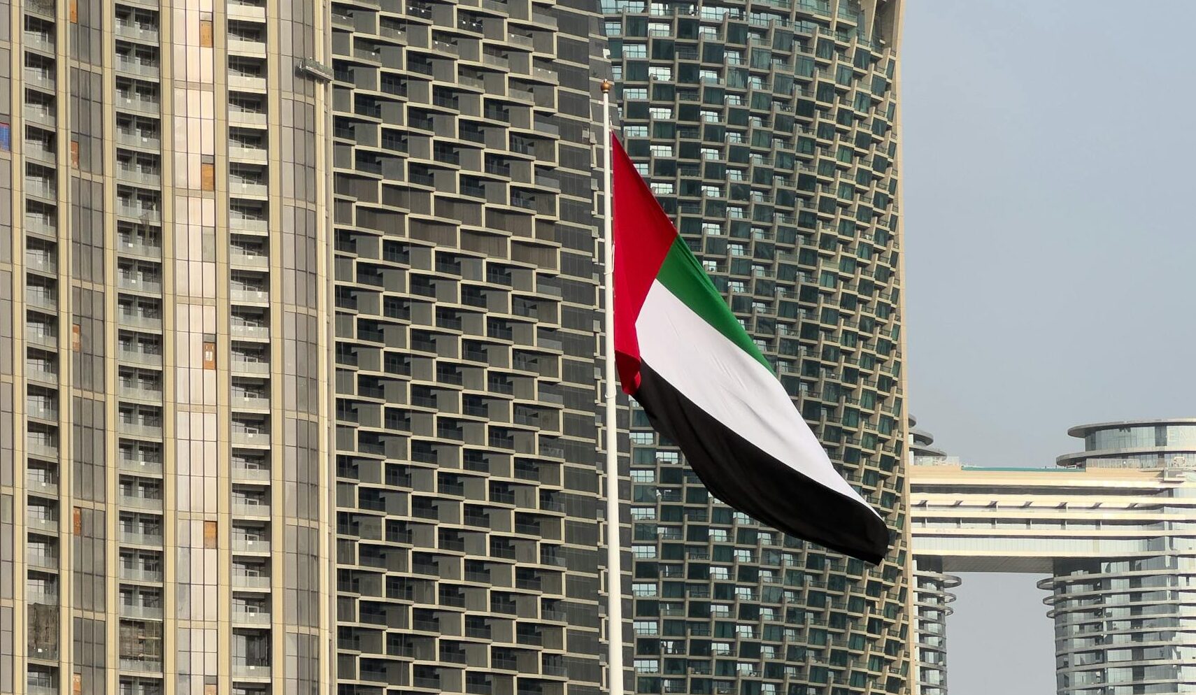 Elegant Dubai skyscraper view with UAE flag flapping, showcasing urban architecture.